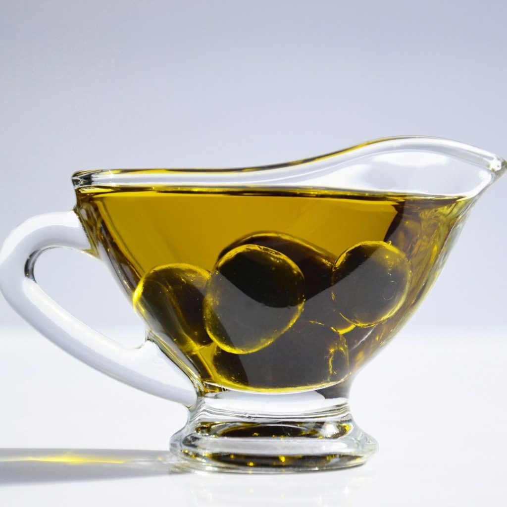 A container is filled with extra virgin olive oil and fresh olives.