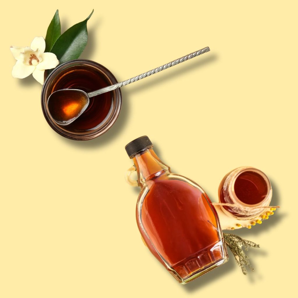 A ramekin of vanilla extract and a bottle of maple syrup are laid together in one frame.