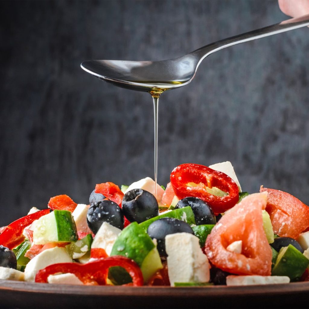 A spoonful of extra virgin olive oil gets poured into a salad plate.