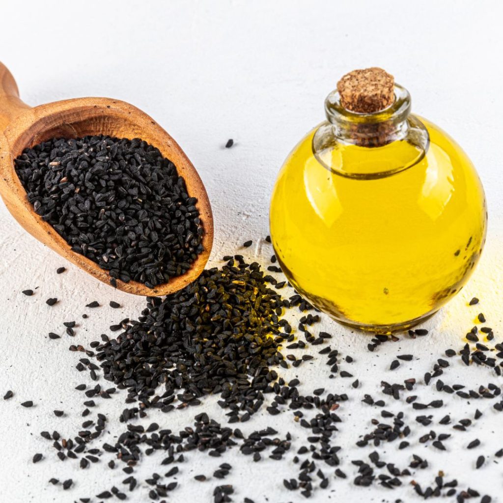 A bottle of seed oil sits on the table with vegetable seeds.