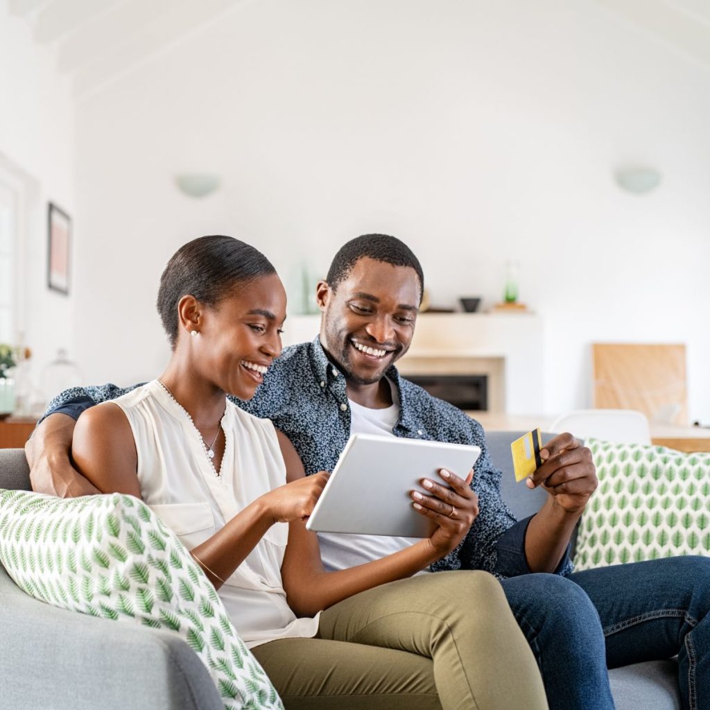 A happy couple using a tablet and holding a credit card