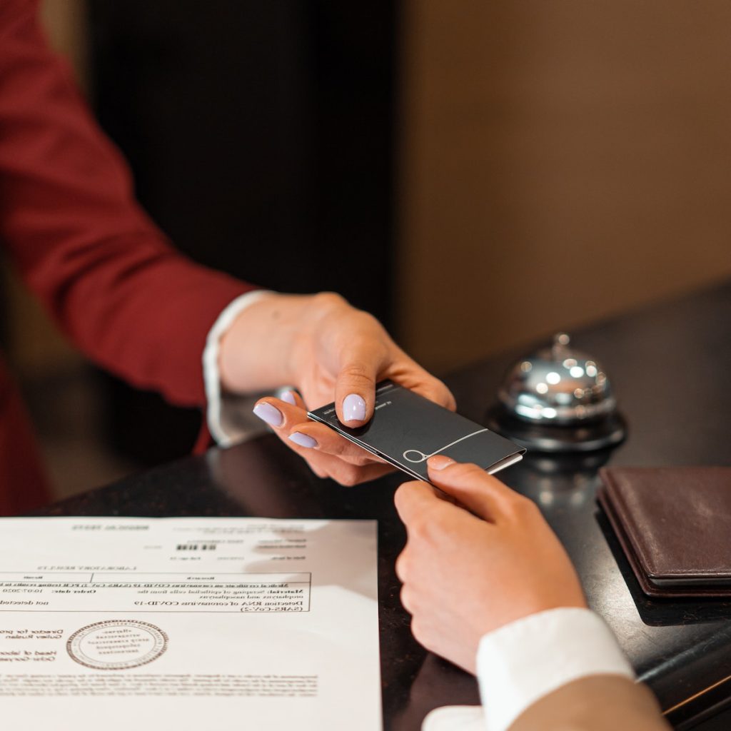 A hotel receptionist handing a key card to a guest