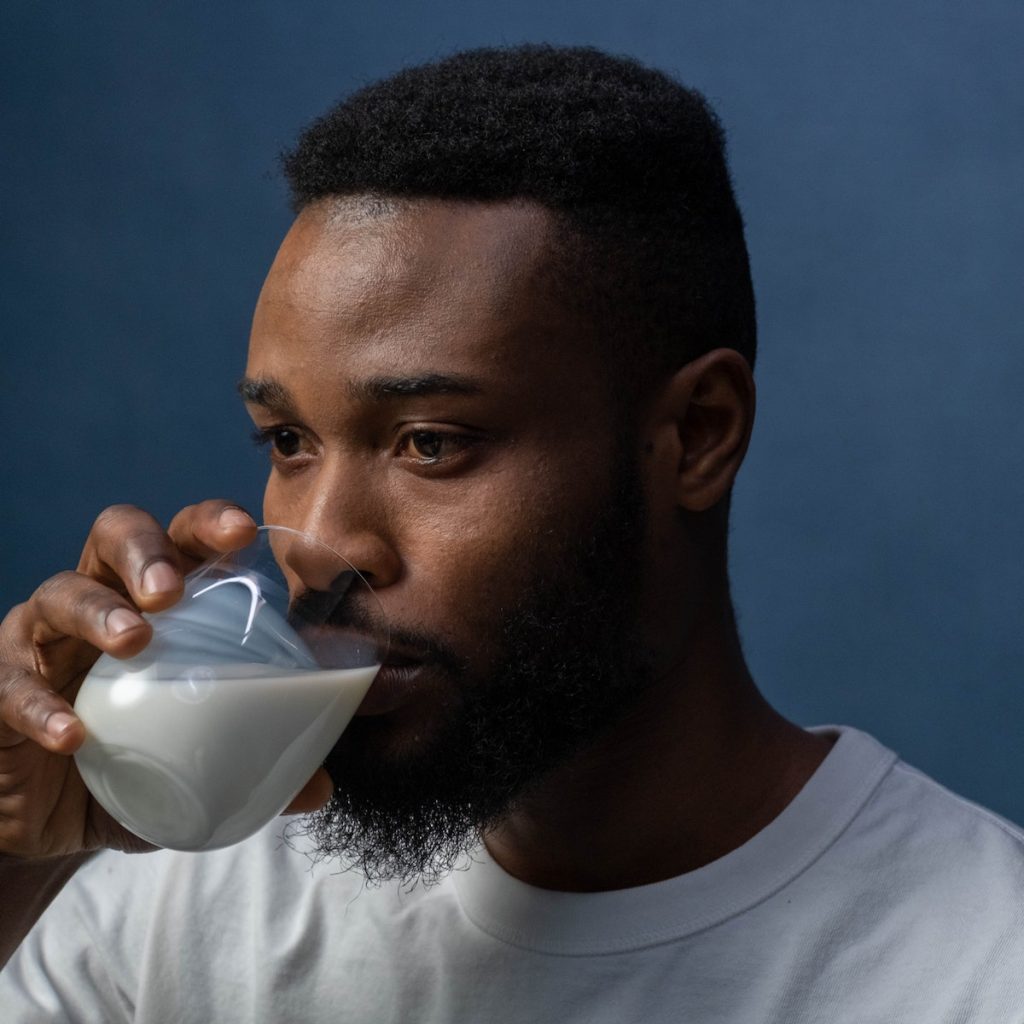 A man drinking a glass of black sesame milk