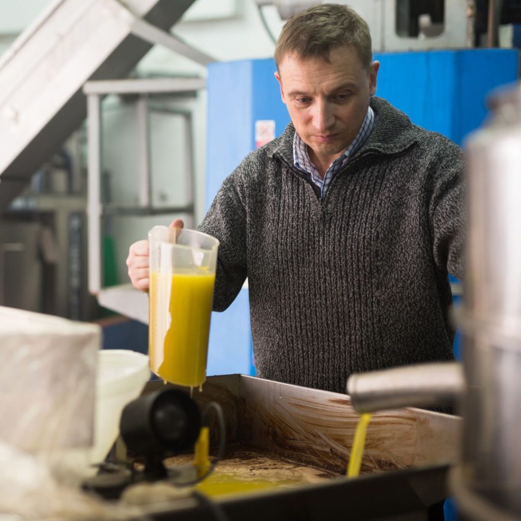 A man works on quality control of extra virgin olive oil in a factory.