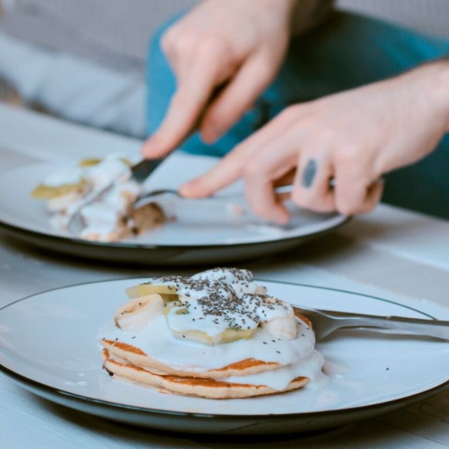 A person eating pancakes with black sesame seeds