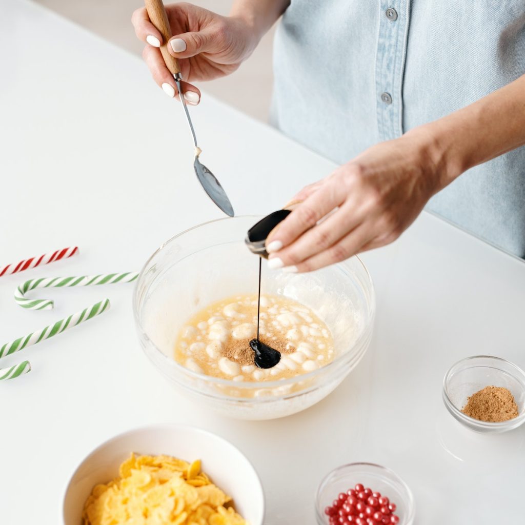 A person pouring vanilla extract in a bowl