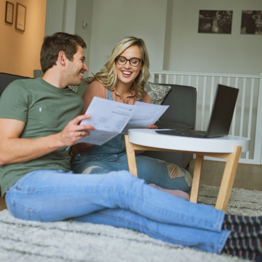 A smiling couple holding a piece of paper while booking on Agoda