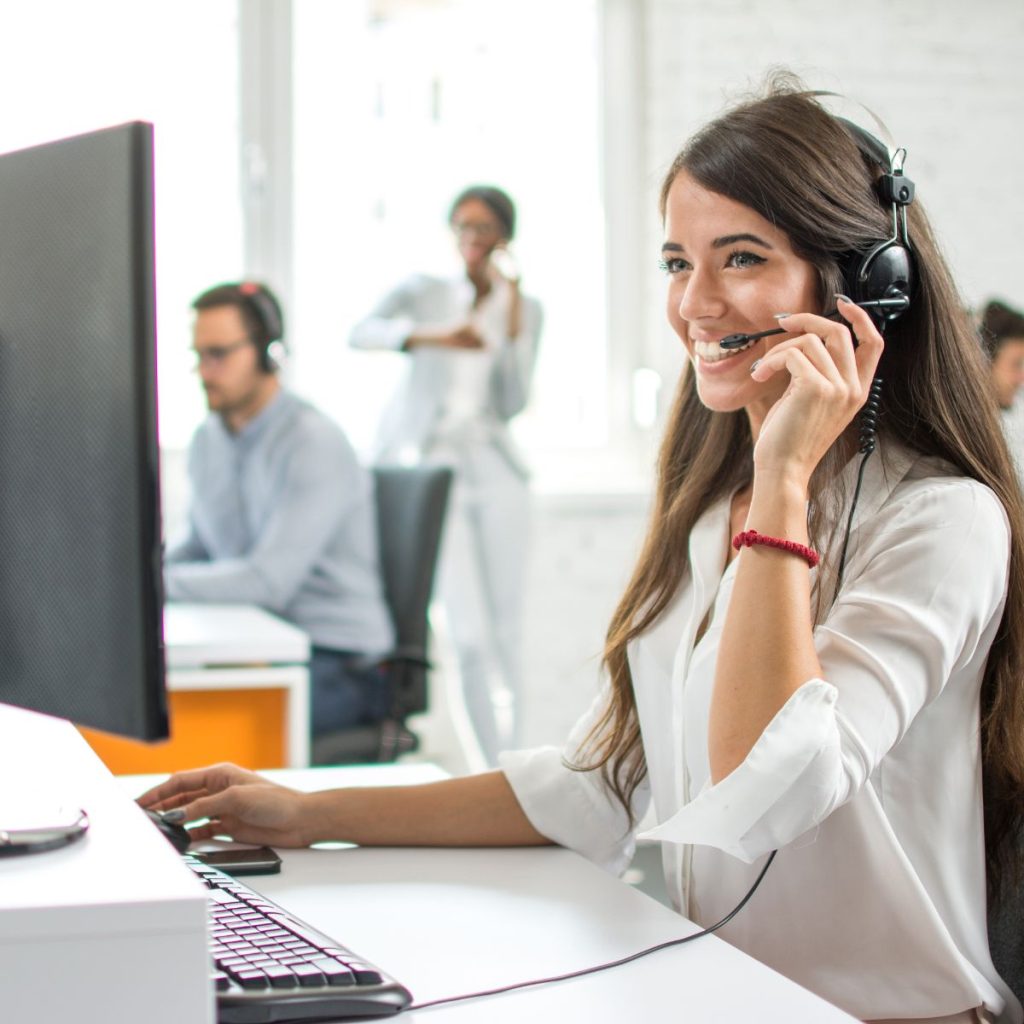 A smiling female customer service operator working on computer in office