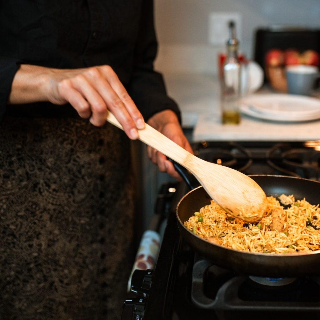 A woman cooking on a pan using a wooden spoon