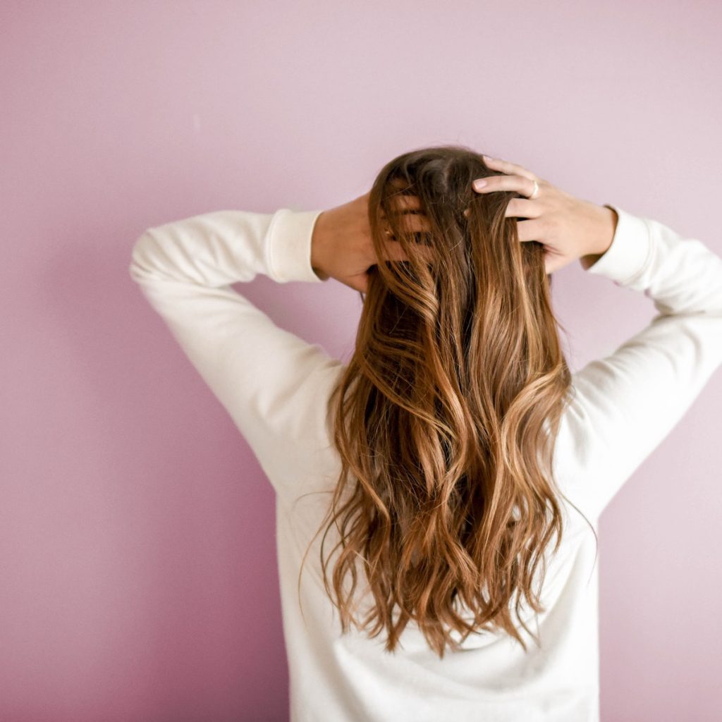 A woman facing the wall while touching her hair