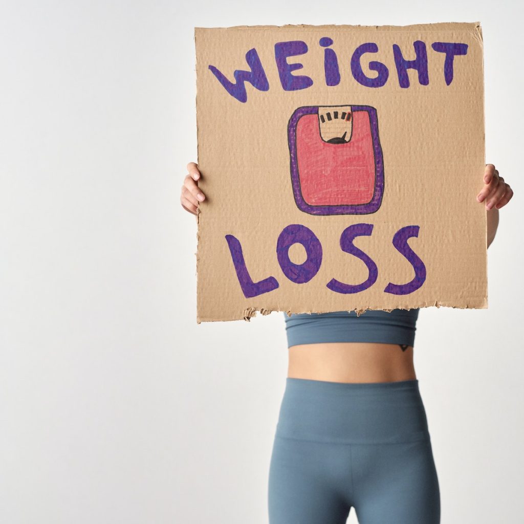 A woman holding a weight loss poster