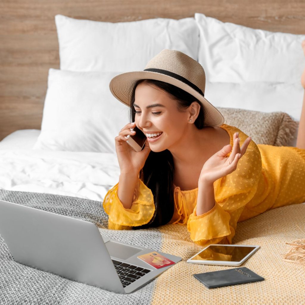 A woman talking on the phone while looking at a laptop