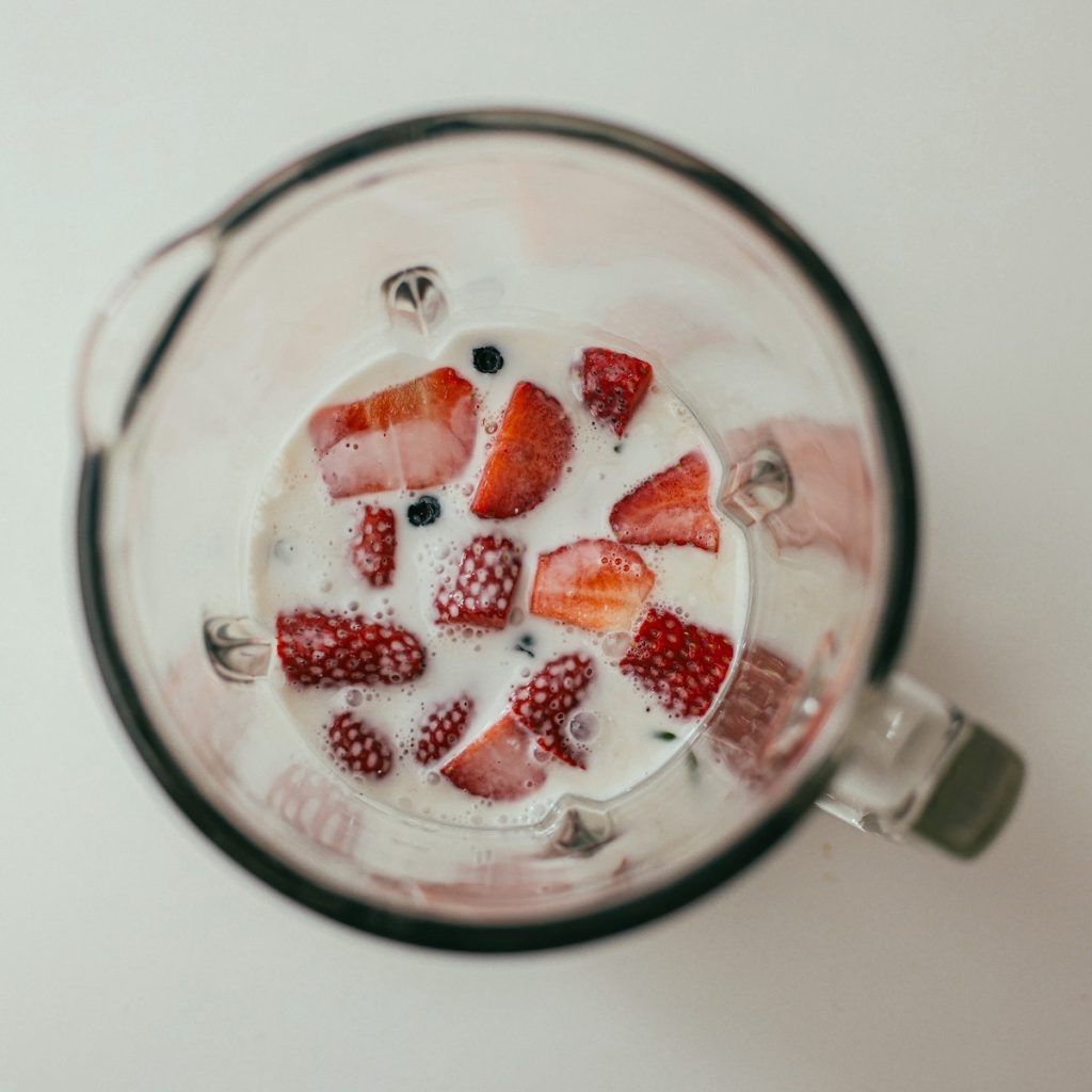 Black sesame milk and slices of strawberry in a blender