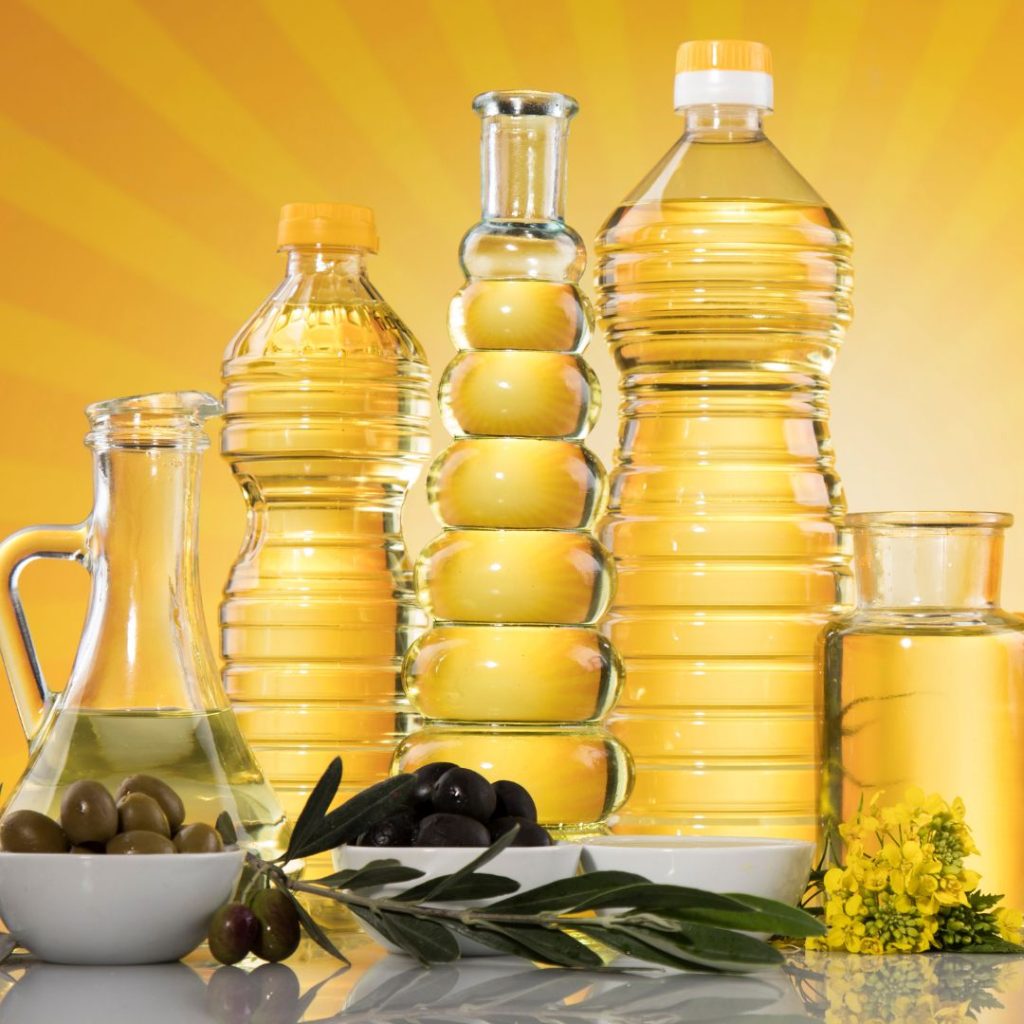 Multiple bottles of oils sit on the table with their fruit and seed sources.