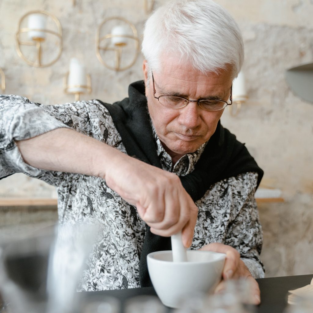 Old man using a mortar and pestle to grind black sesame seeds