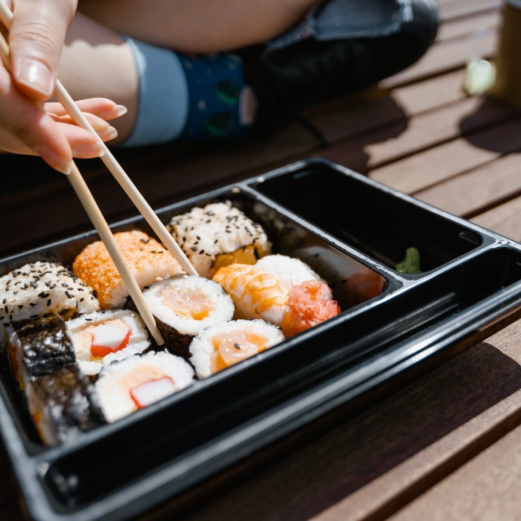 Person eating sushi with black sesame seeds