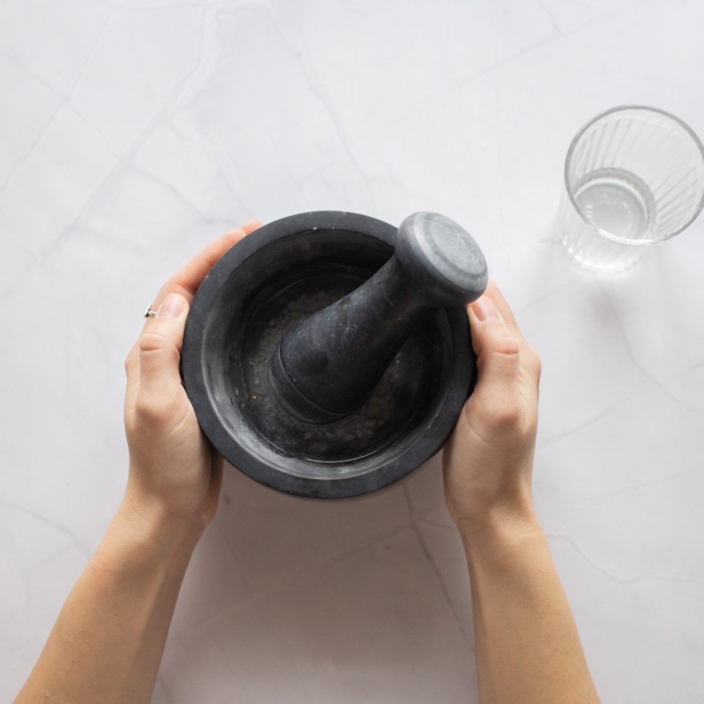 Person holding a mortar and pestle, making a black sesame paste