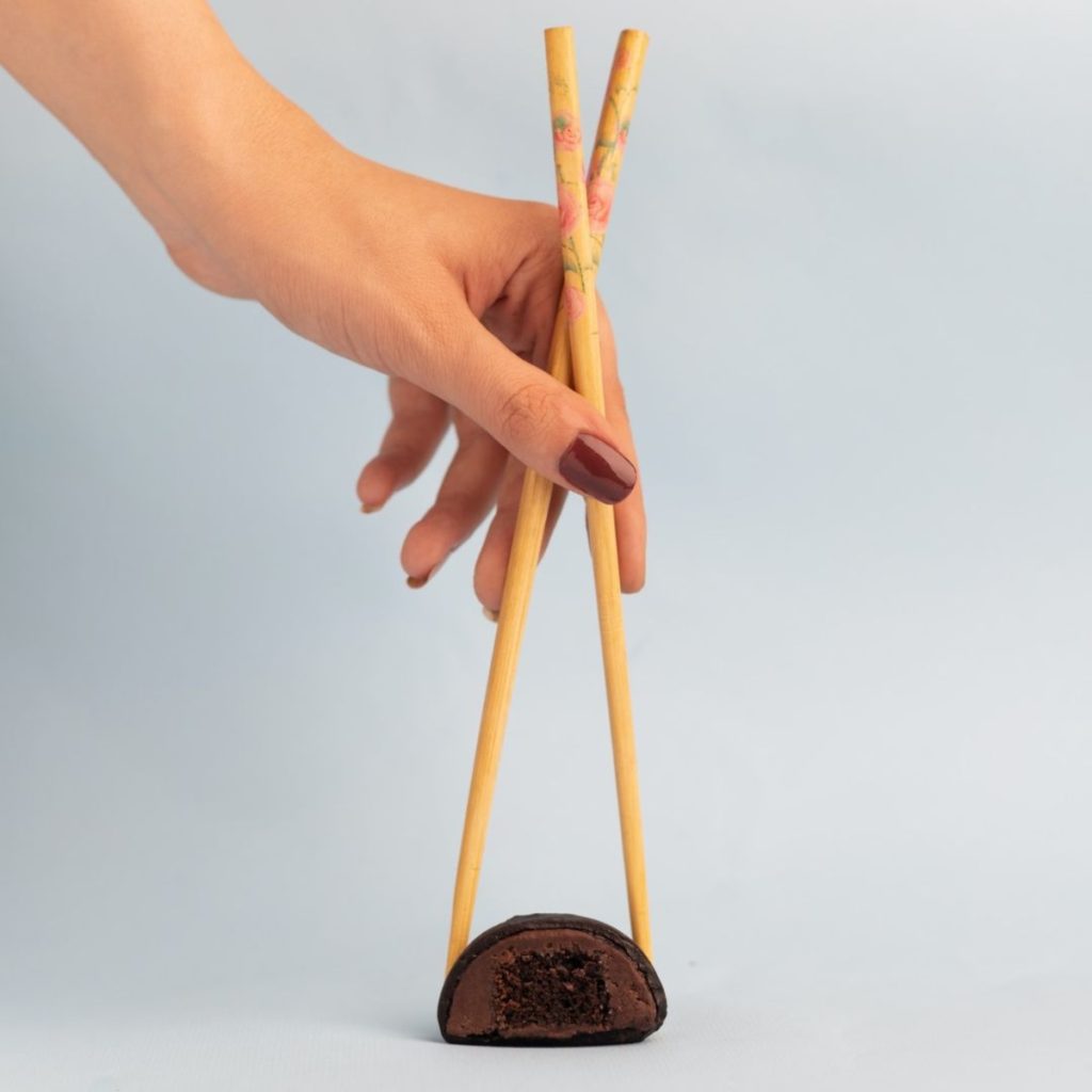 Person using chopsticks to pick up a black sesame mochi