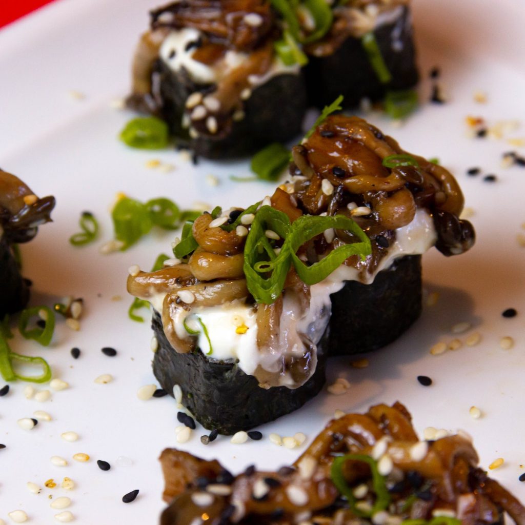 Sushi rolls on a plate sprinkled with white and black sesame seeds