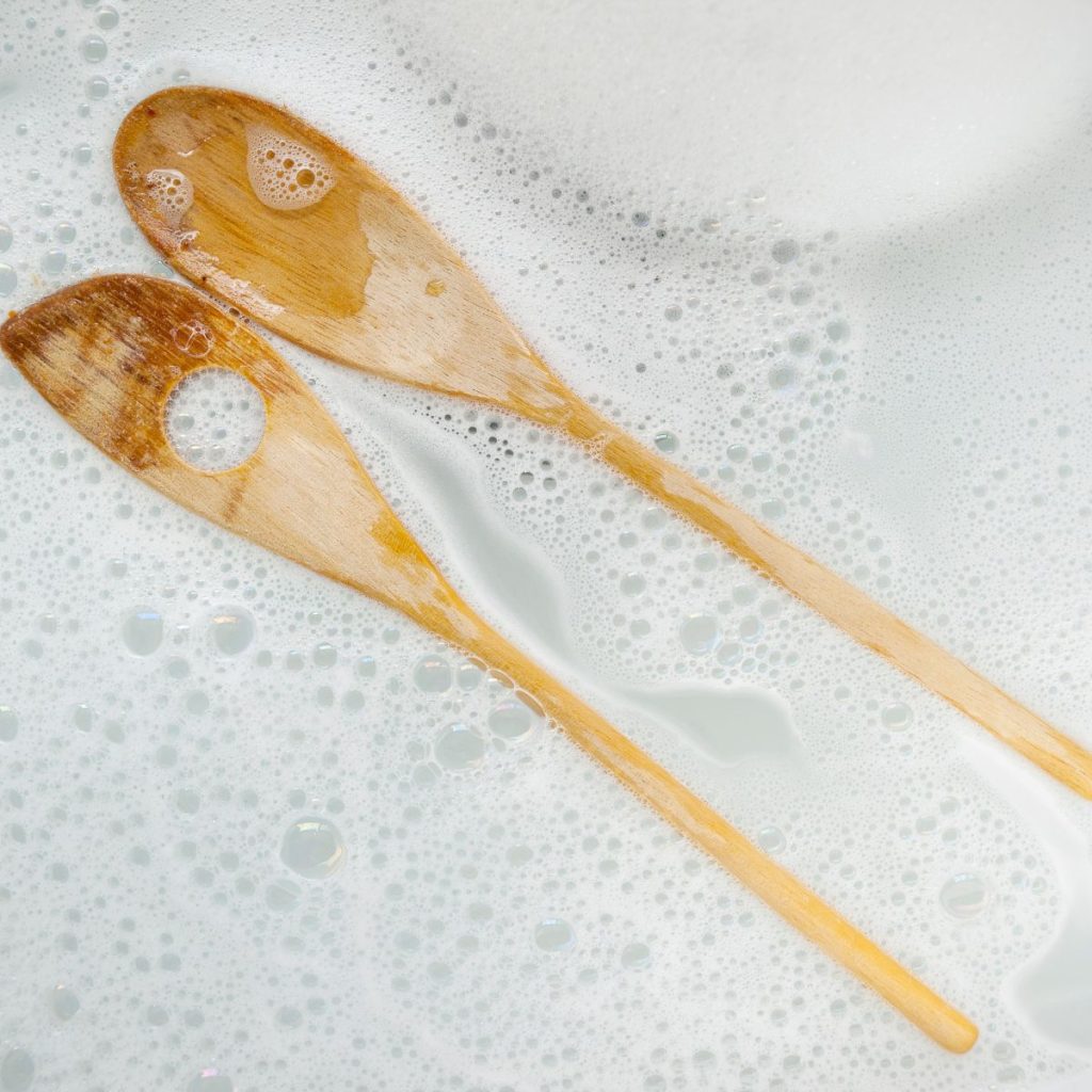 https://alldayieat.com/wp-content/uploads/2023/10/Two-wooden-spoons-soaked-in-soapy-water-1024x1024.jpg