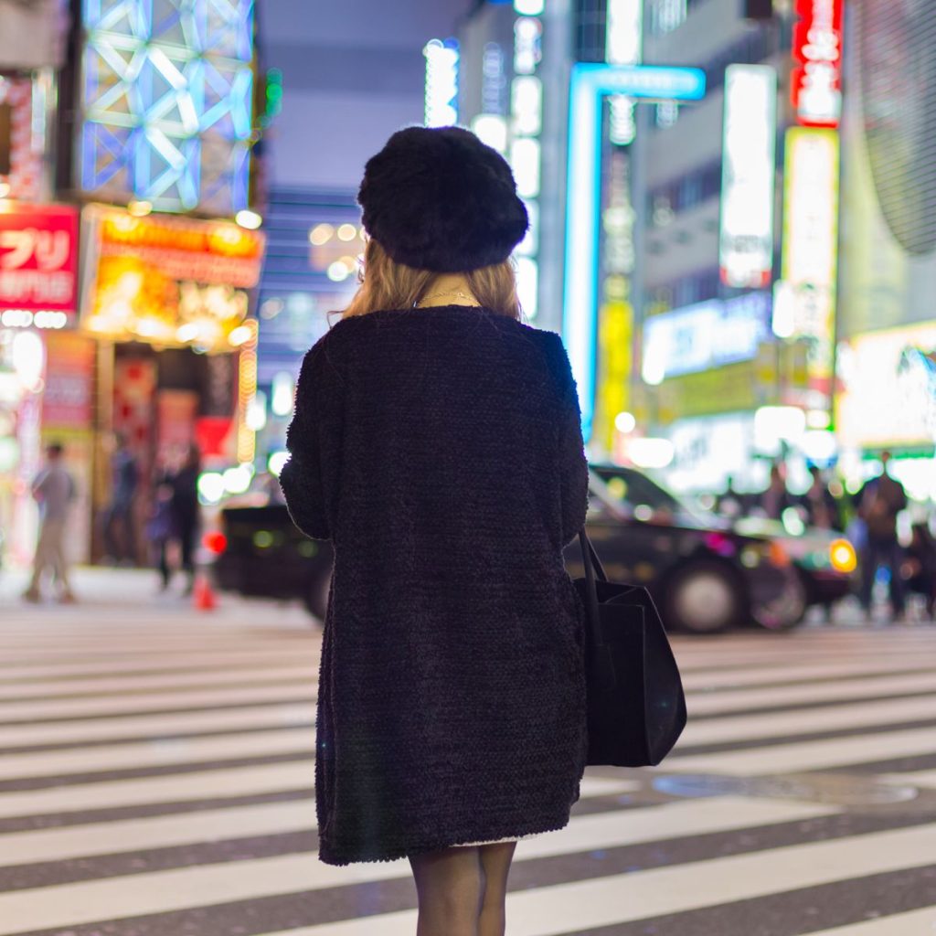 Woman in black coat in busy street of Japan