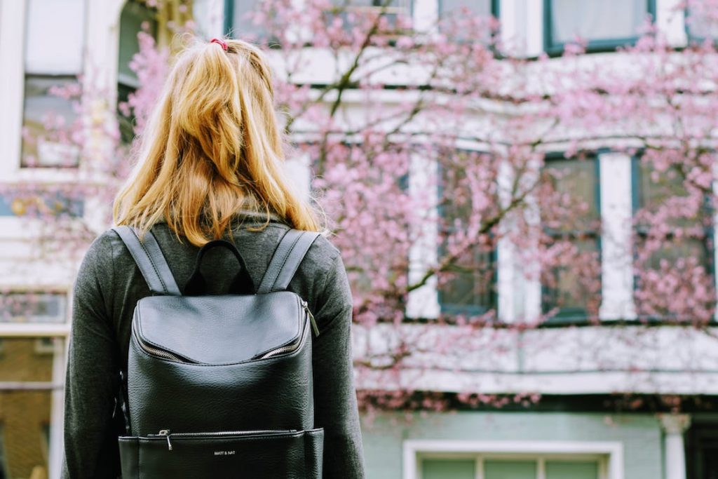 Solo Japan Travel featuring a girl with a backpack with sakura tree in the background