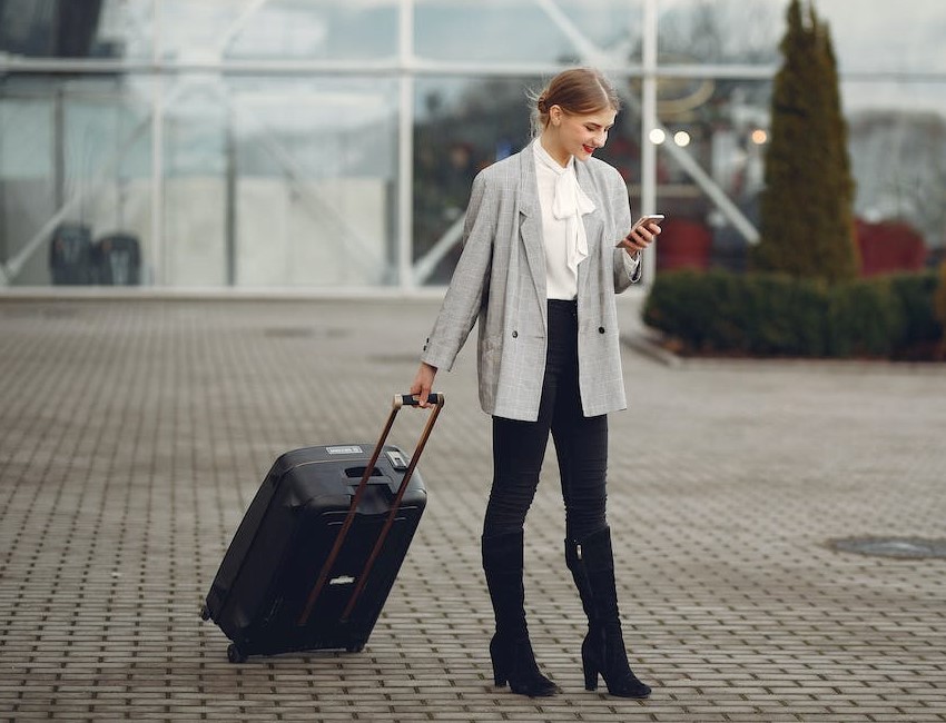 lady browsing phone while carrying a suitcase