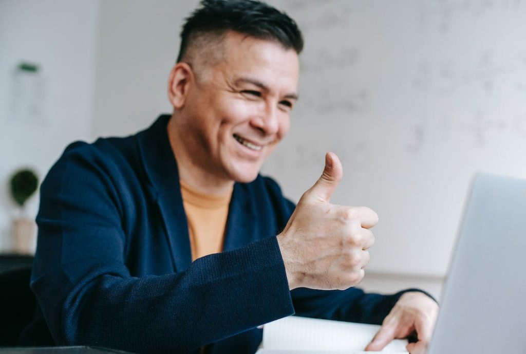 man giving a thumbs up in front of the laptop