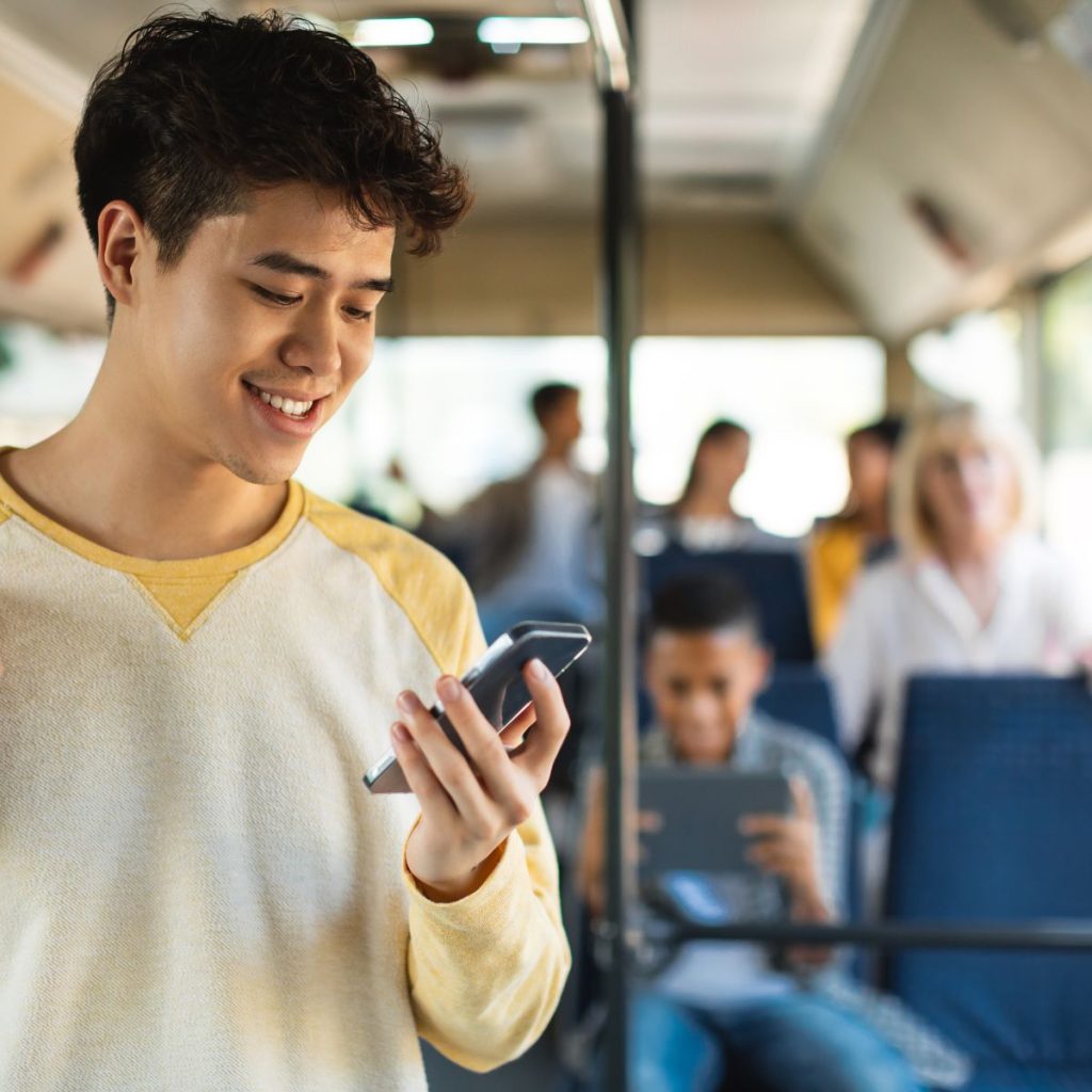 a man wearing yellow longsleeves using phone on a bus ride