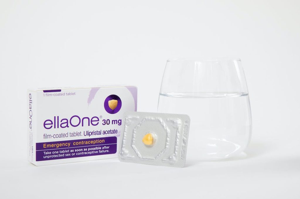 contraceptive in a box and a glass of water