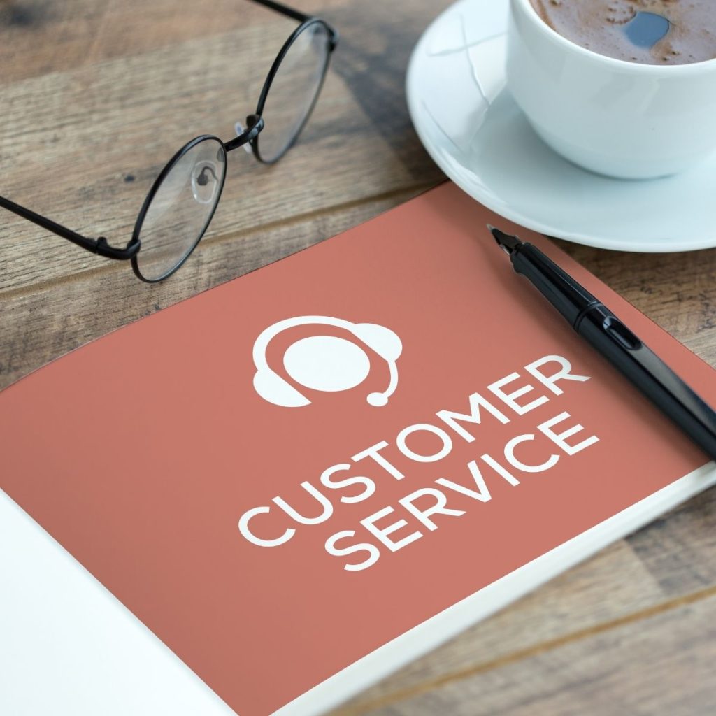 A booklet with the text "customer service" printed on its surface rests on a wooden table.