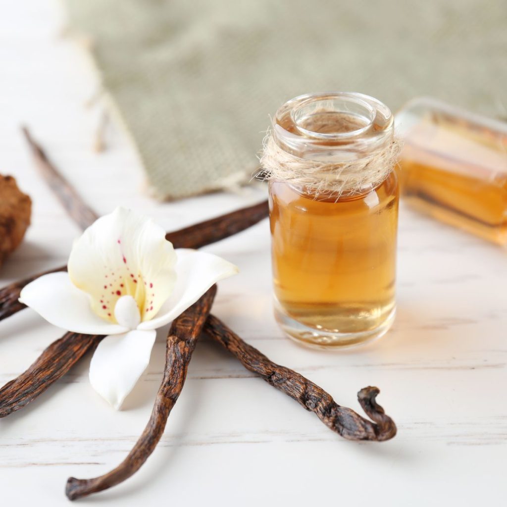 Glass bottles with vanilla extract on wooden table