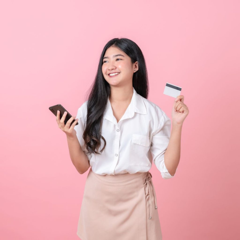 Smiling woman holding a credit card and a phone