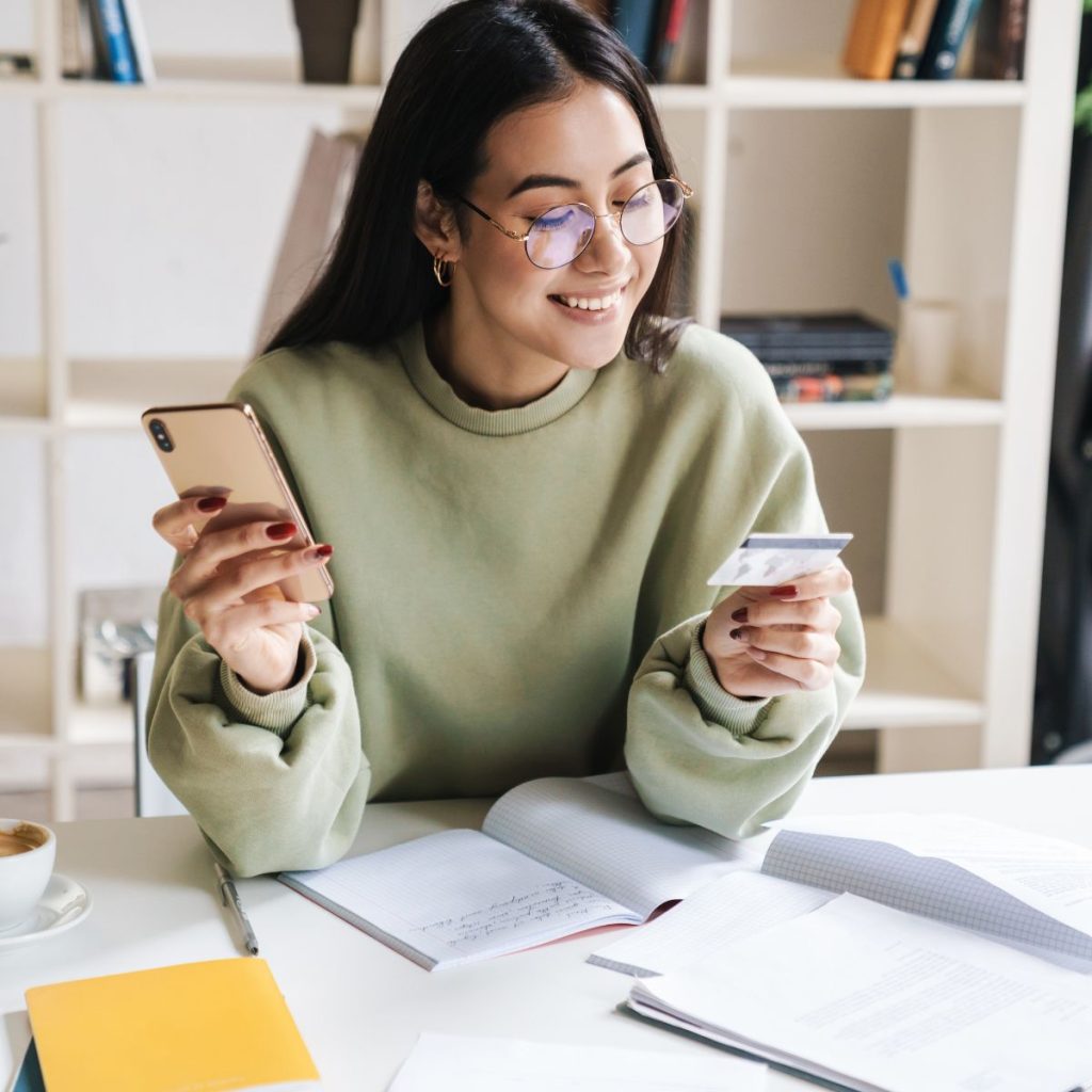 Woman smiling while holding a phone and a credit card