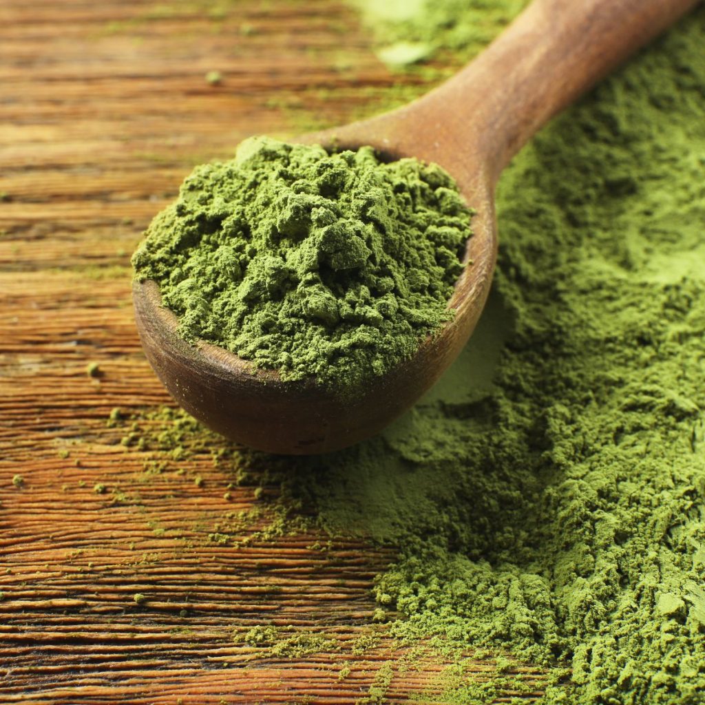 Wooden Spoon with Powdered Matcha Green Tea on Wooden Table