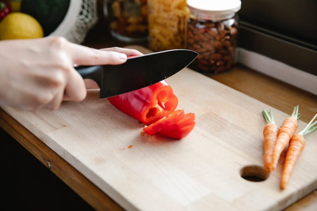 Best Kitchen Knife Sets Under $100 featuring a black knife cutting vegetables