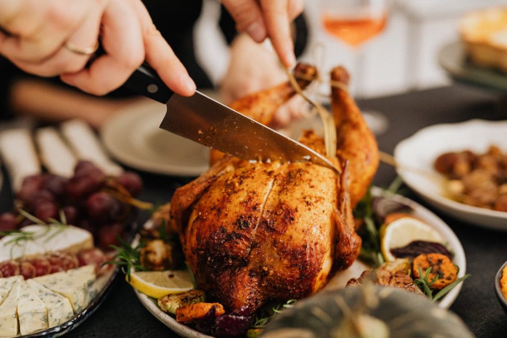 Best Kitchen Knife Sets Under $100 featuring someone cutting roasted chicken using a knife 