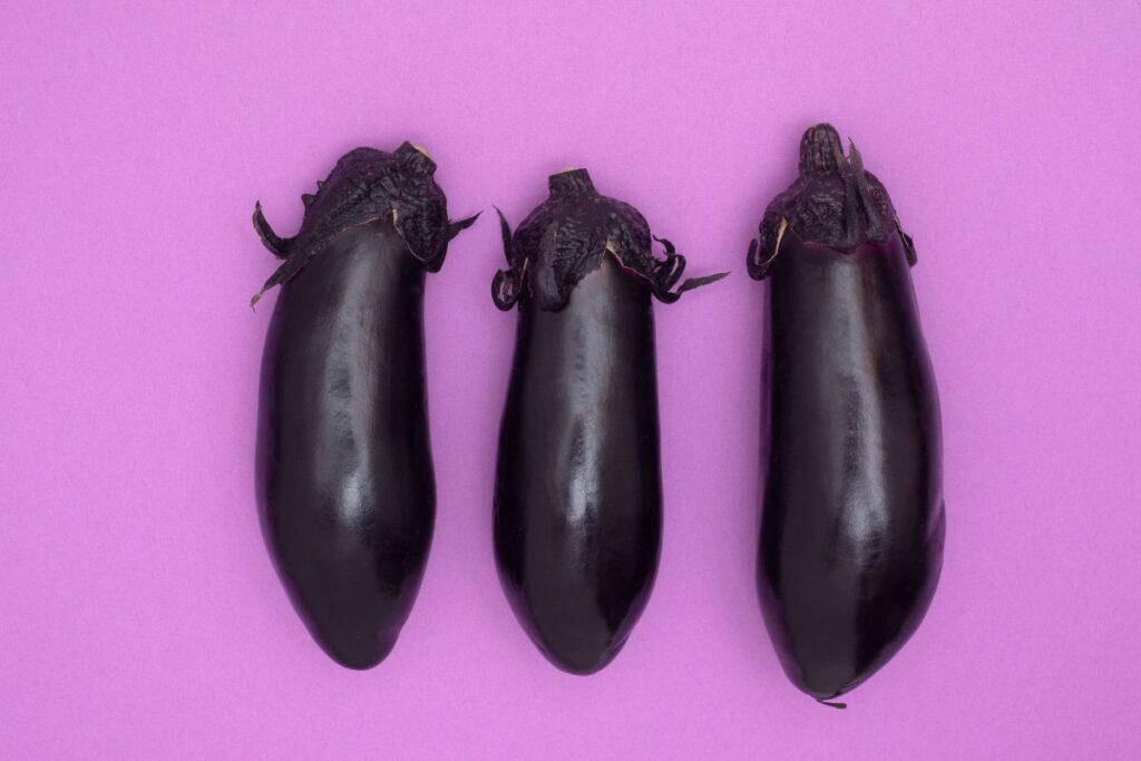 Japanese eggplant lined up on a violet surface