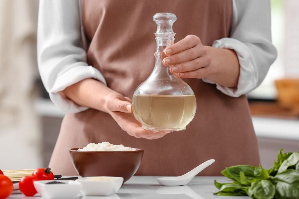 A woman holding a bottle of rice vinegar in a kitchen